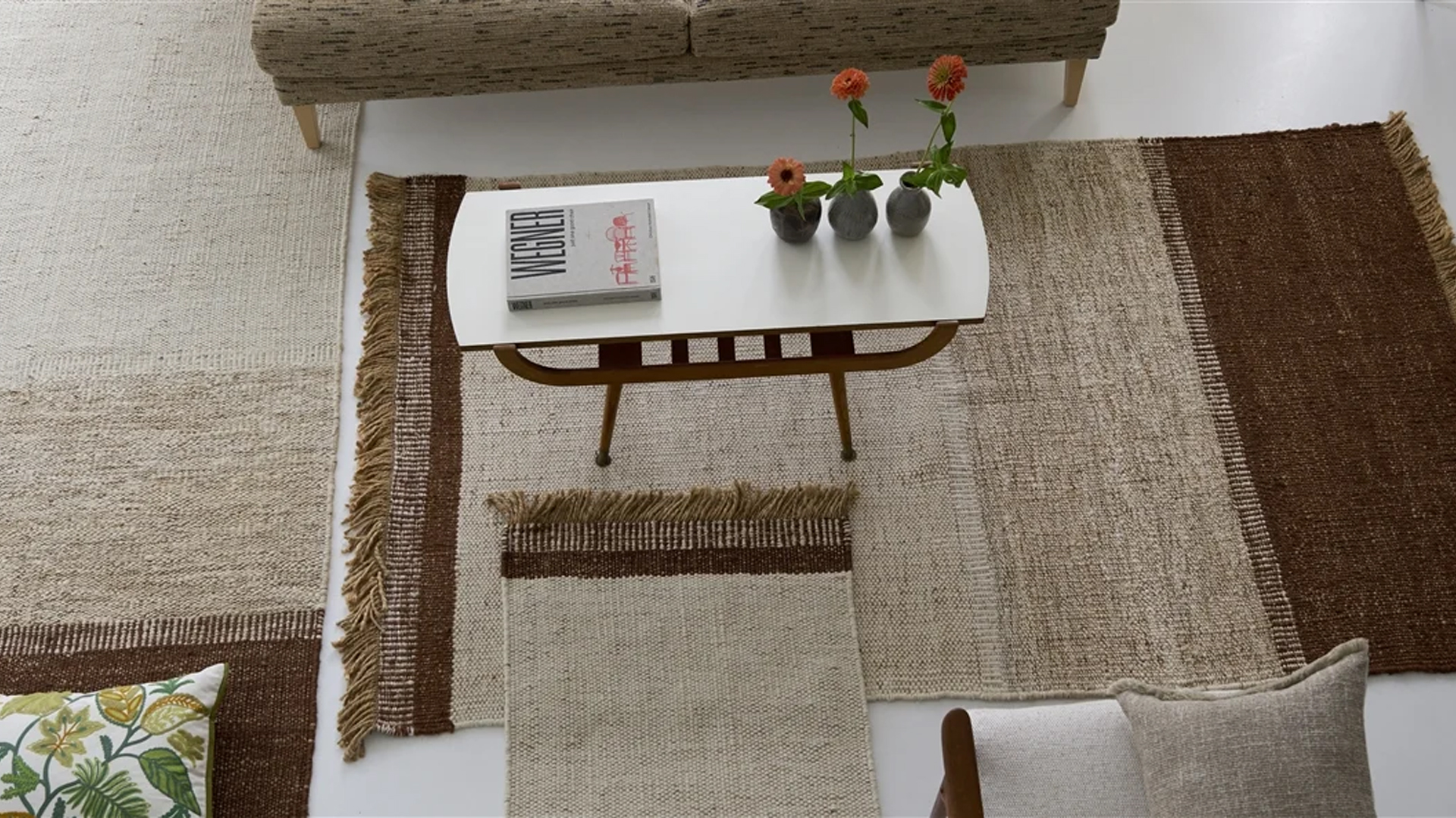 Neutral and brown flat weave rugs layered around a white coffee table for a relaxed summer interior