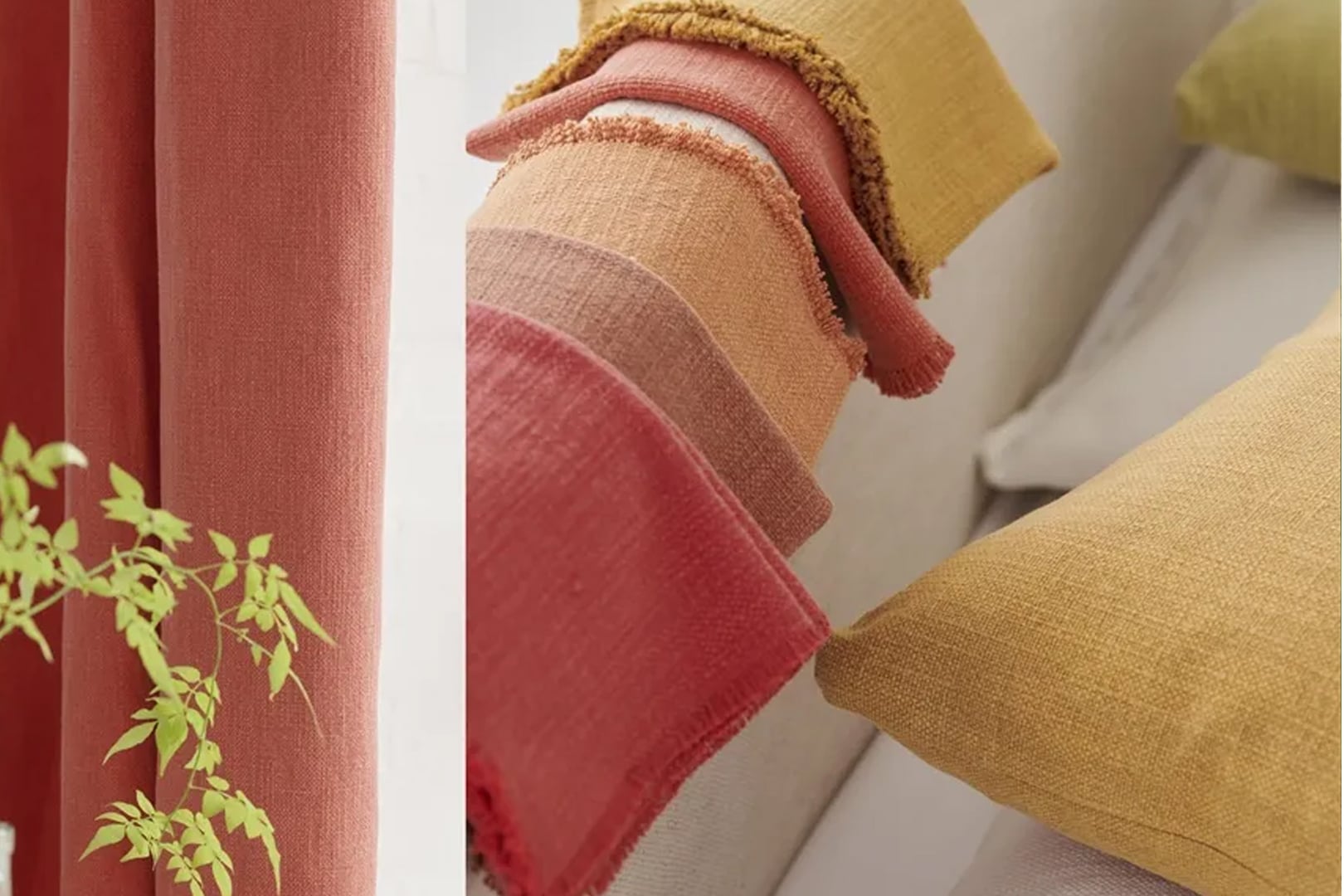 Colourful cotton upholstery fabrics arranged with coral, pink and ochre cushions