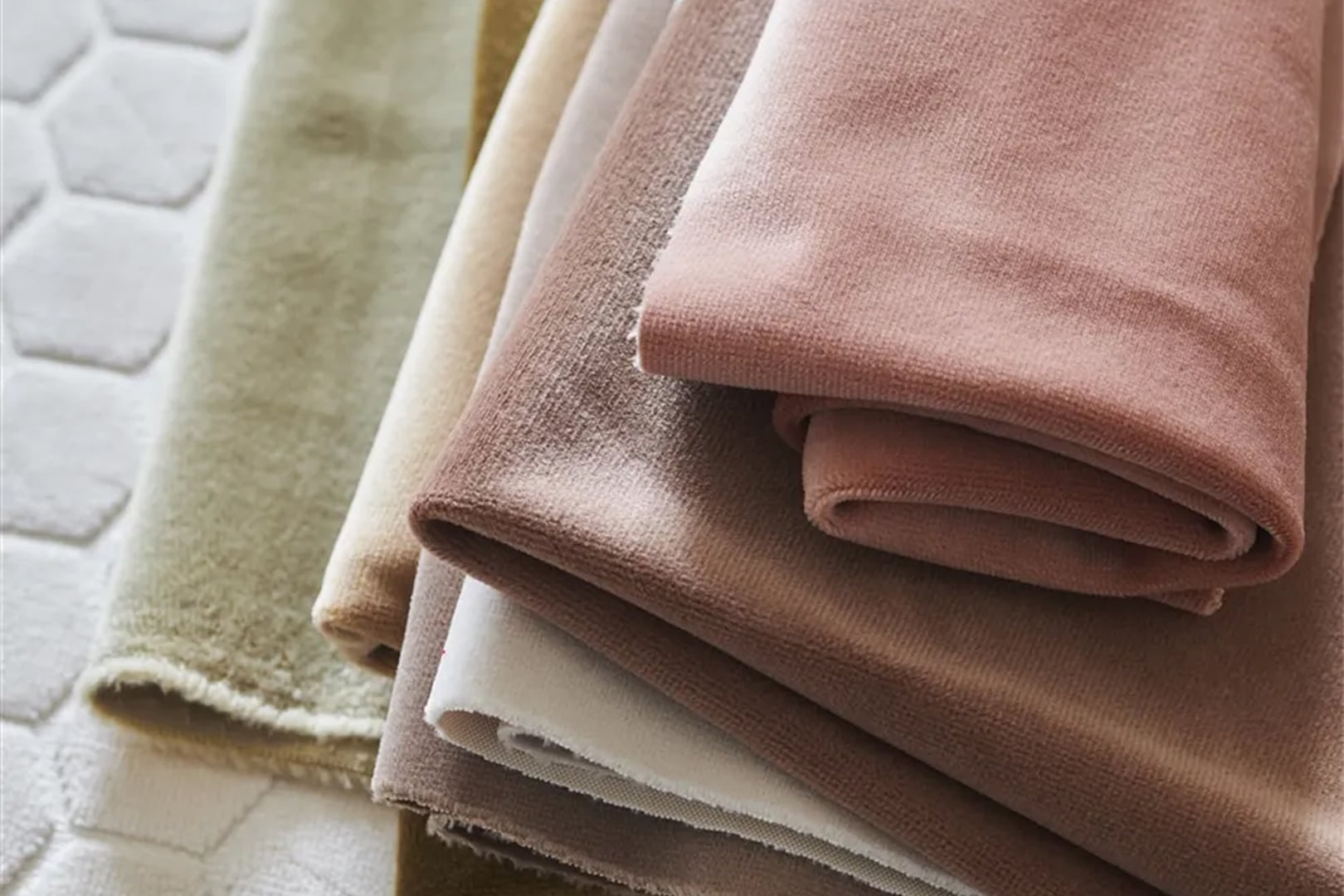 A layered selection of blush, rose and neutral velvet upholstery fabrics