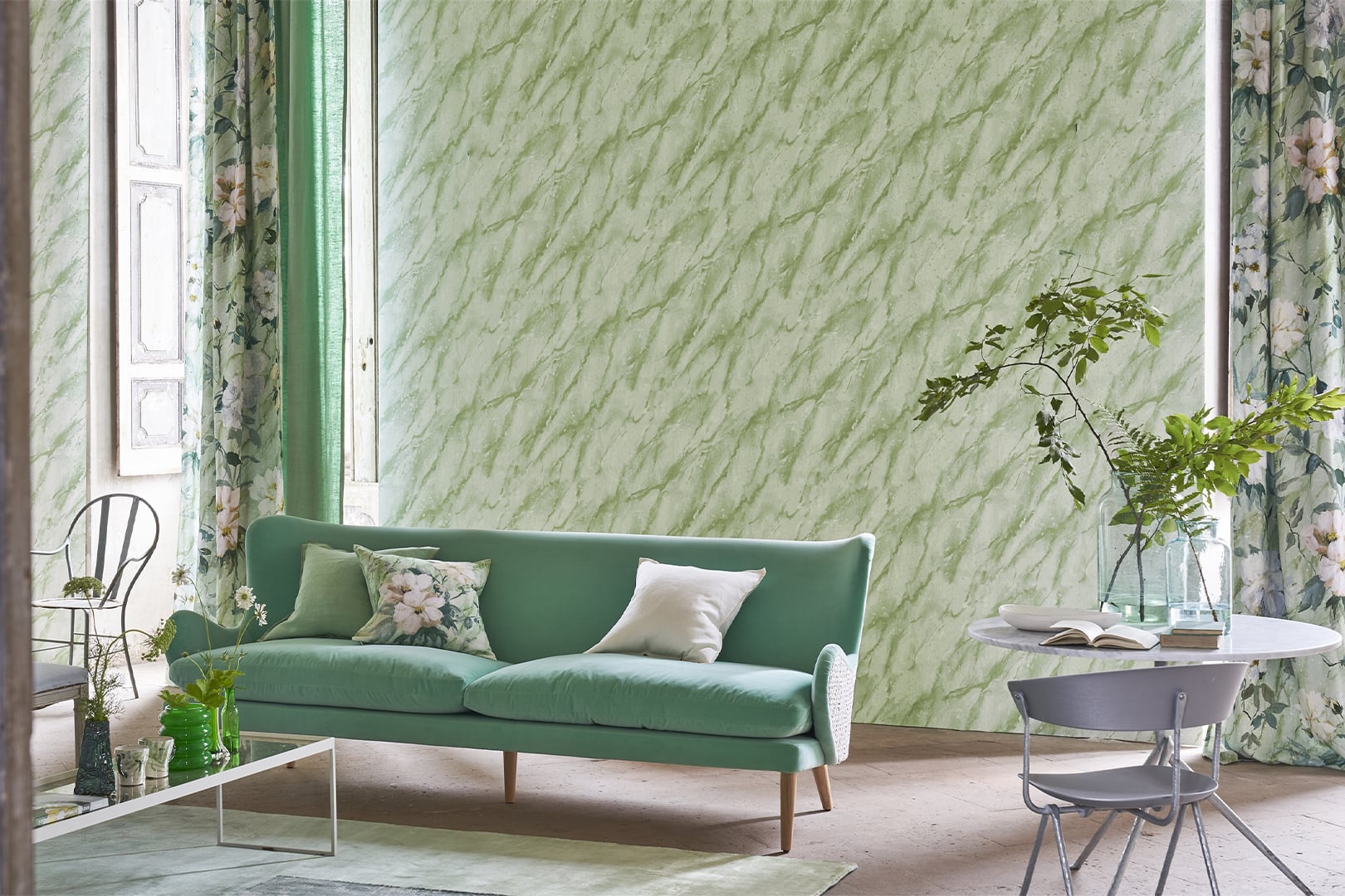 Green marble-effect wallpaper with textured surface behind a pale sofa