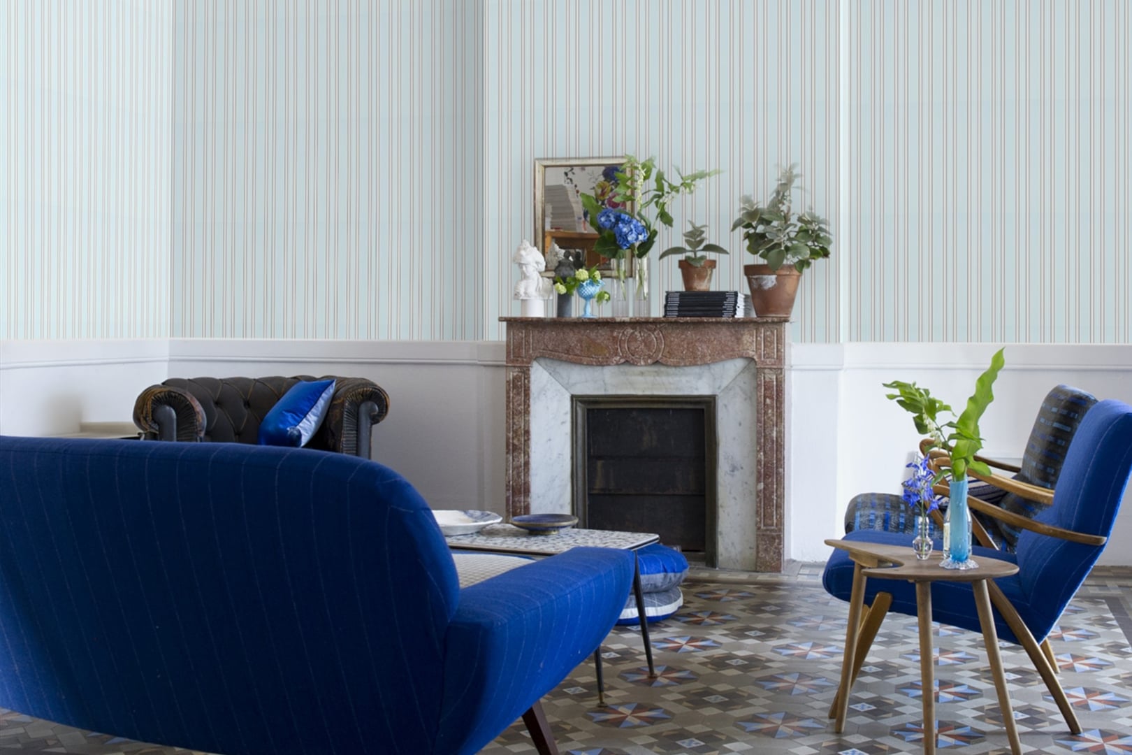 Interior with pale vertical striped wallpaper, fireplace and deep blue chair