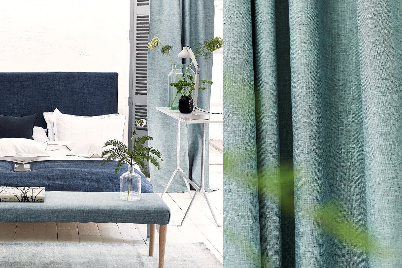 Muretto blackout curtain fabric by Designers Guild shown in a blue bedroom scheme with textured aqua drapery